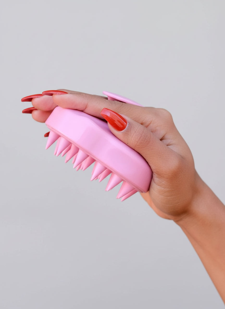 Hand holding a pink brush against a green leafy background